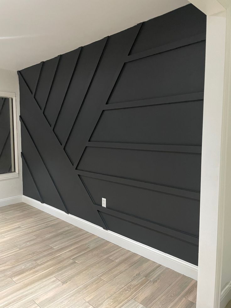 an empty room with wood flooring and black painted wall art work on the walls