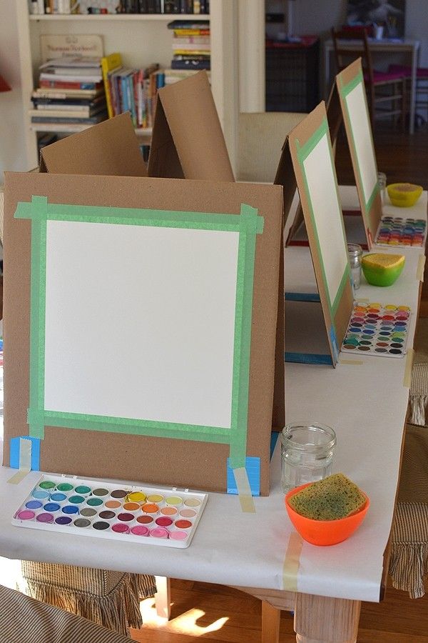 there is a table that has some art supplies on it, including an easel and paintbrushes