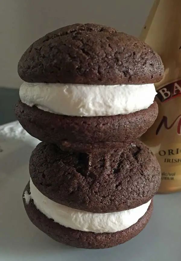 three cookies with ice cream on them are stacked next to a bottle of milk,