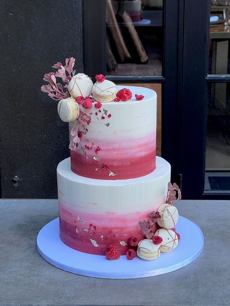 a three tiered cake with pink and white frosting on a blue platter