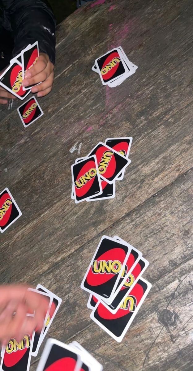 people playing uno uno cards on a wooden table