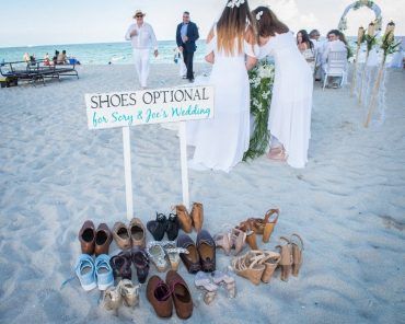 two women standing next to each other on top of a beach with shoes in front of them