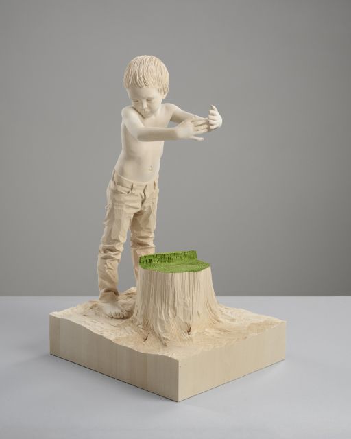 a statue of a boy standing on top of a stump