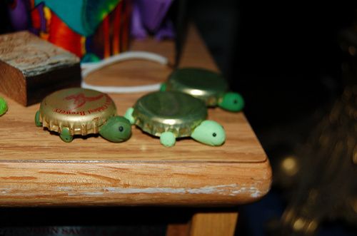 two small green turtles sitting on top of a wooden table next to a slice of bread