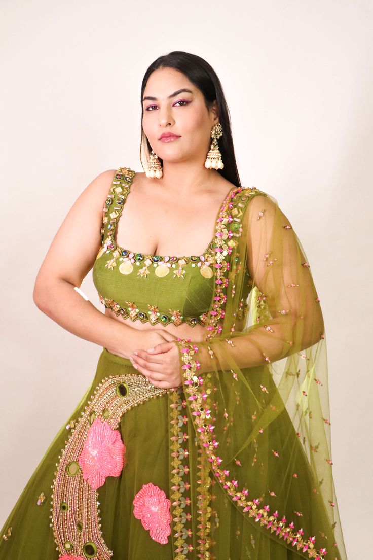 Introducing a tulle lehenga in olive, adorned with glass beads, metals, sequins, and 3D embroidered flowers. Paired elegantly with an olive raw silk blouse embellished with shell stones, crystals, and metals, along with a complementing tulle dupatta. This ensemble combines intricate detailing with a touch of glamour for a captivating look. Pista Green Lehenga With Intricate Embroidery For Party, Festival Hand-embellished Tissue Silk Lehenga, Festival Hand Embellished Tissue Silk Lehenga, Festive Hand Embellished Tissue Silk Lehenga, Festive Hand Embellished Raw Silk Choli, Green Embellished Pre-draped Saree For Wedding, Designer Hand Embellished Raw Silk Choli, Designer Wear Hand Embellished Raw Silk Choli, Anarkali Style Hand Embellished Organza Choli