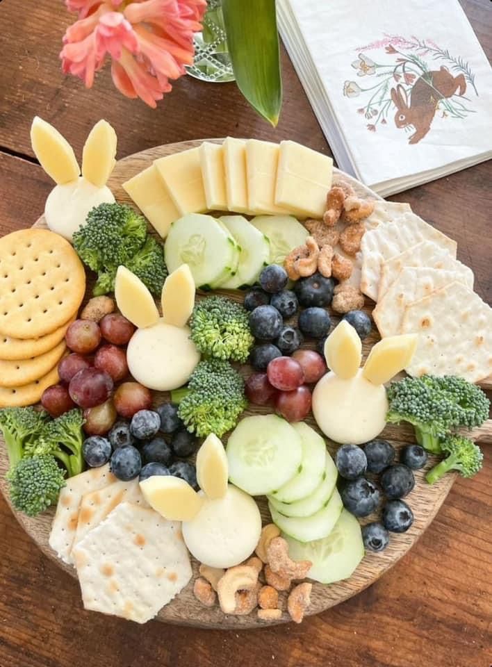 a platter filled with cheese, crackers, grapes, broccoli and blueberries