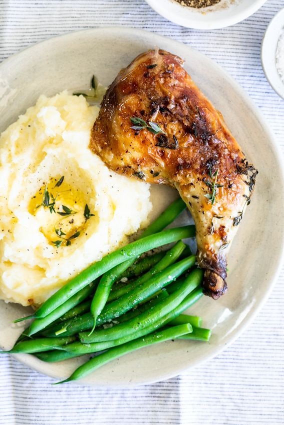 a plate with mashed potatoes, green beans and chicken on it next to two bowls of gravy