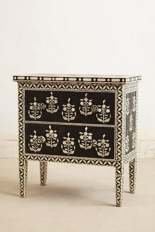 an ornate black and white chest of drawers