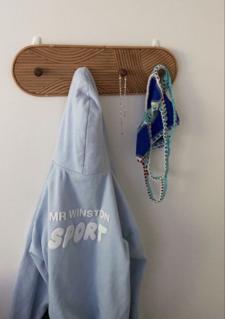 a blue hoodie hanging on a wall next to a pair of sunglasses and necklaces