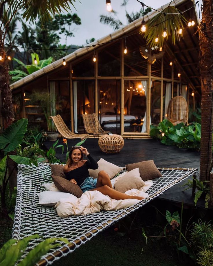 a woman sitting in a hammock with pillows on it