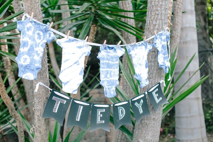 some clothes hanging from a line with the words tie dye on them in front of palm trees