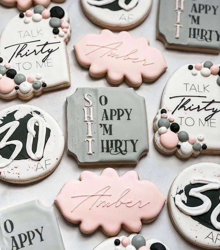 decorated cookies that are on top of a white table with black and pink decorations in the shape of letters