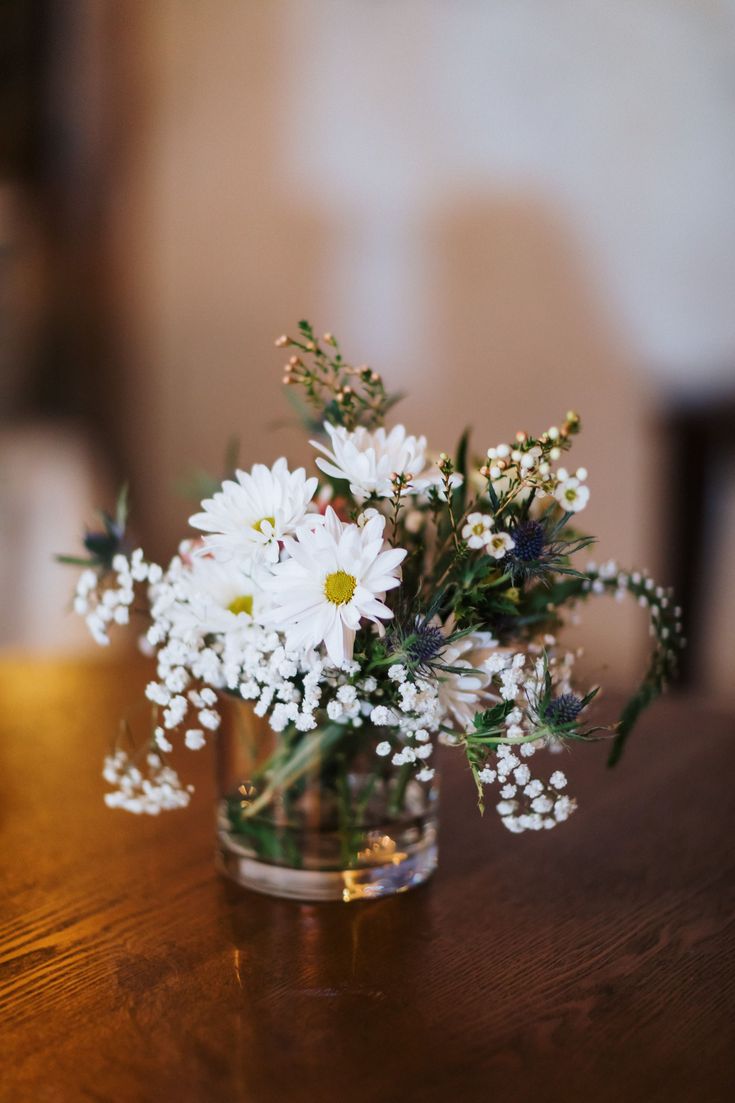 a vase filled with white flowers on top of a wooden table