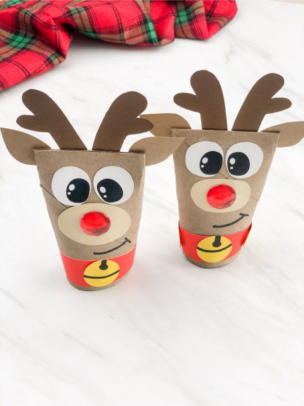 two paper cups with reindeer faces on them sitting on a white counter top next to a red plaid napkin