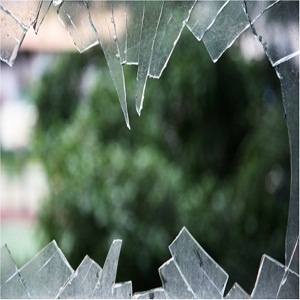 a broken glass window with trees in the background