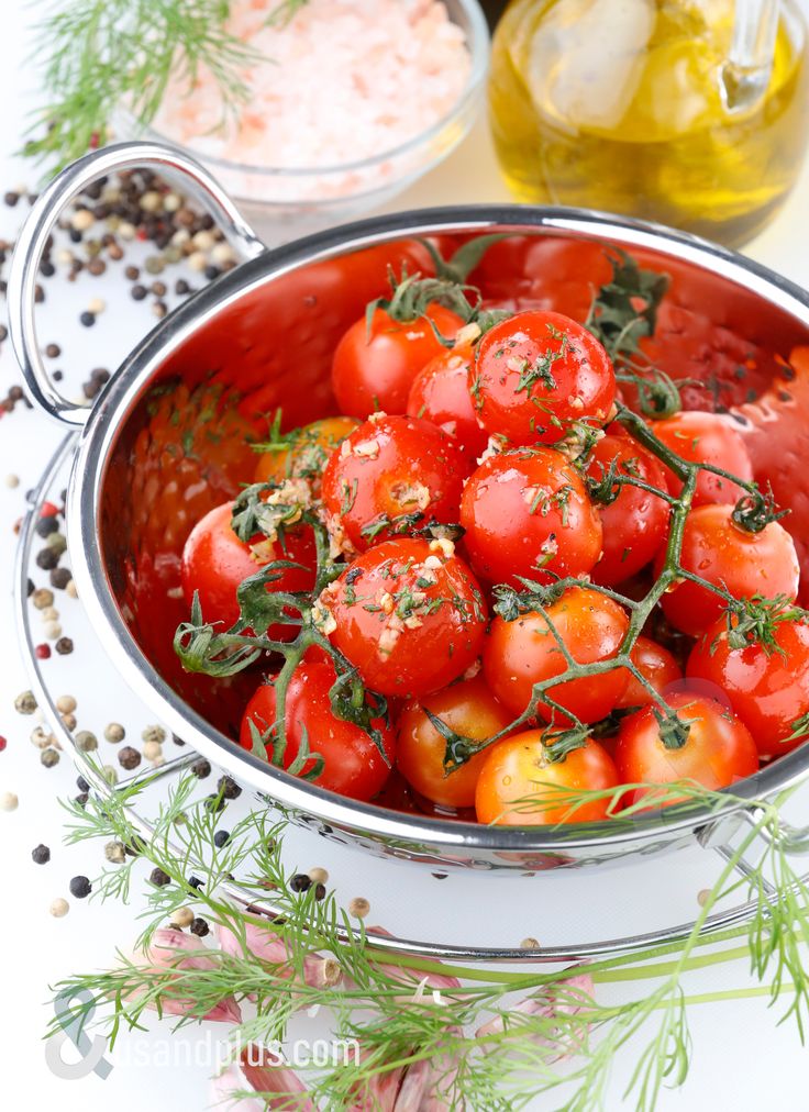 a bowl filled with tomatoes and herbs on top of a table