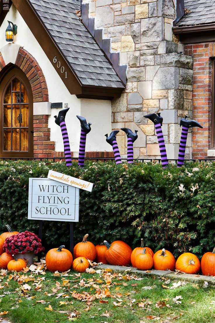 pumpkins are lined up in front of a house with witches on their heads and striped stockings