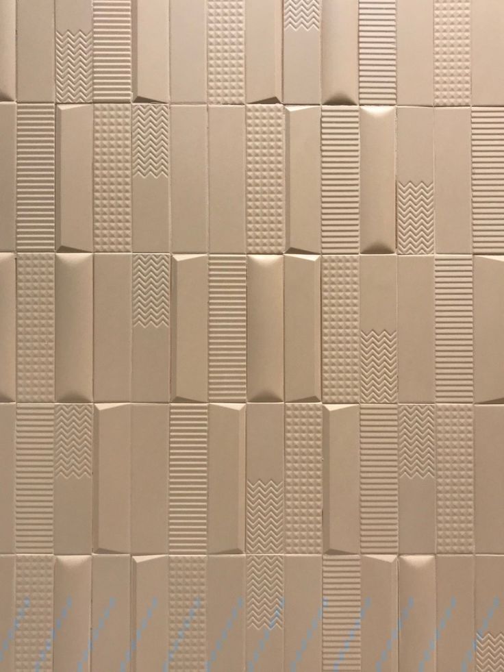 the wall is made up of many different sized pieces of white tile with small squares on each side