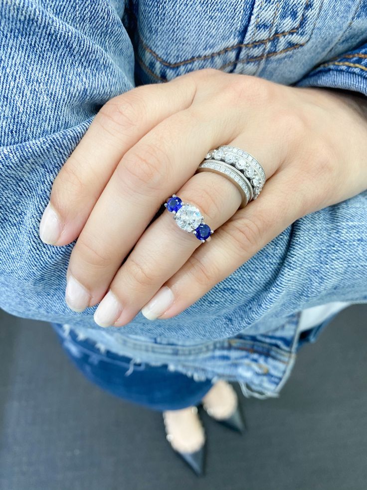 a woman's hand with three different rings on her left and the middle finger