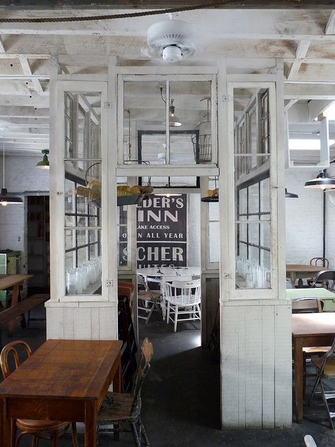 an empty restaurant with tables and chairs in the center, surrounded by white painted walls