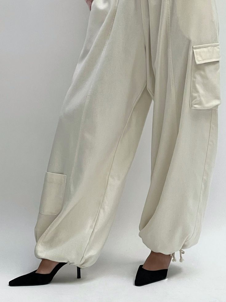 The Cooper Cargo Pant in our perennial favorite fabric, silk canvas, features a structured yet warm silk hand quintessentially perfect across all seasons. The Cooper features a comfortable yet elegant elastic + drawstring waistline, easy side and utilitarian pockets, and adjustable ties at the bottom to allow for a balloon silhouette or wide leg fit. We truly love this updated classic for its ease of styling and functionality - the Cooper Cargos share endless possibilities from day to evening af Beige Cargo Pants With Pockets For Loungewear, Loungewear Straight Parachute Pants With Pockets, Straight Parachute Pants With Pockets For Loungewear, Loungewear Parachute Pants With Pockets, Straight Parachute Pants For Loungewear, Beige Harem Pants For Loungewear With Pockets, Relaxed Fit Cargo Pants With Drawstring For Work, Beige Harem Pants For Loungewear, Wide-leg Parachute Pants With Cargo Pockets For Loungewear