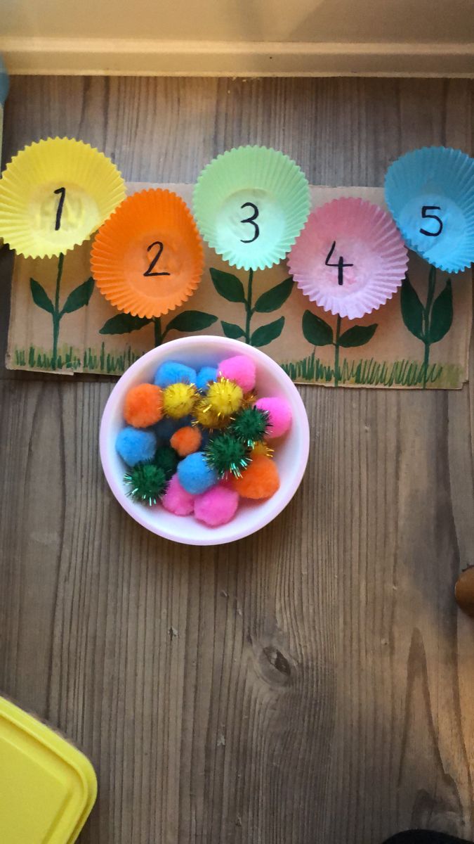 a bowl filled with colorful balls next to a number line on a wooden table top