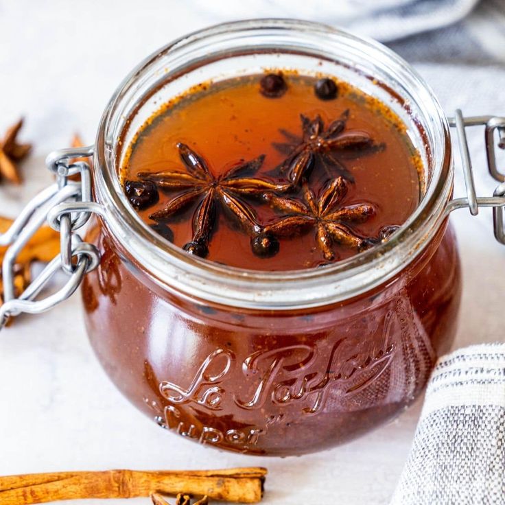 a jar filled with liquid sitting on top of a table next to some cinnamon sticks