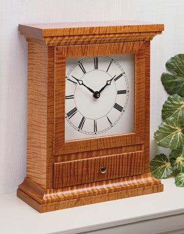 a wooden clock sitting on top of a white shelf next to a green leafy plant