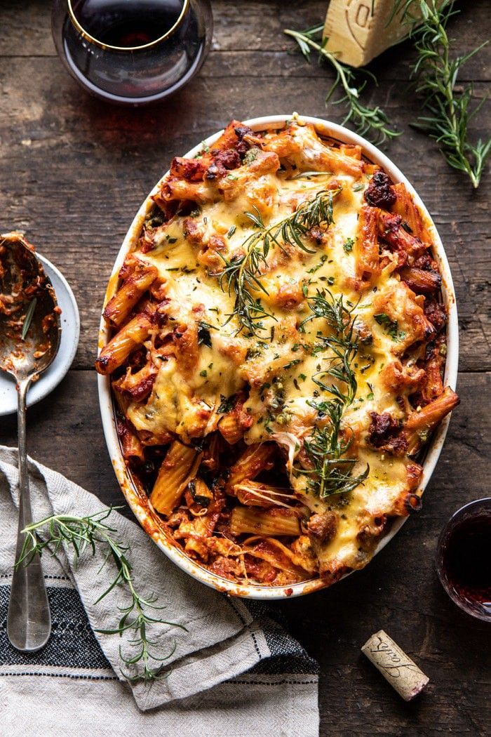 a casserole dish with meat, cheese and herbs in it on a wooden table