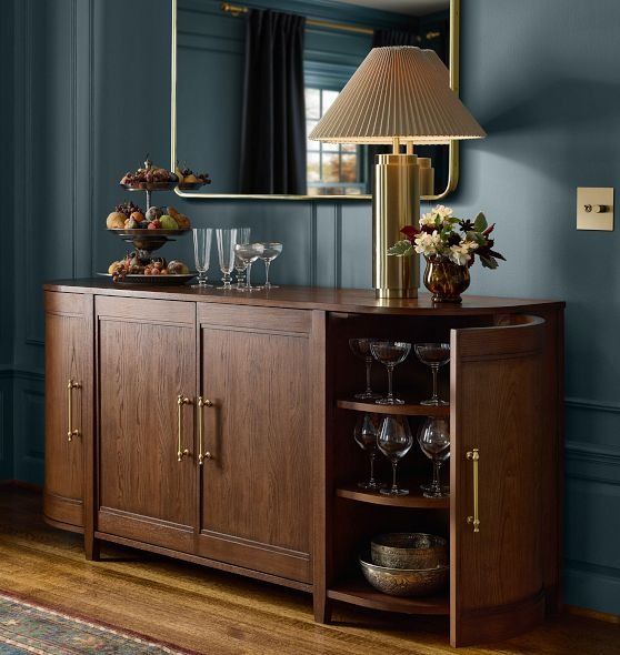 a buffet table with wine glasses on it and a lamp in the corner next to it