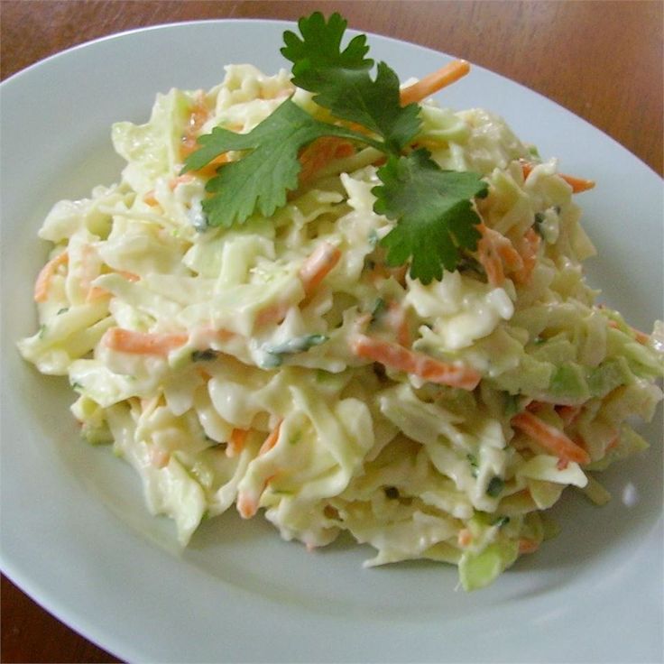 a white plate topped with coleslaw and garnished with cilantro