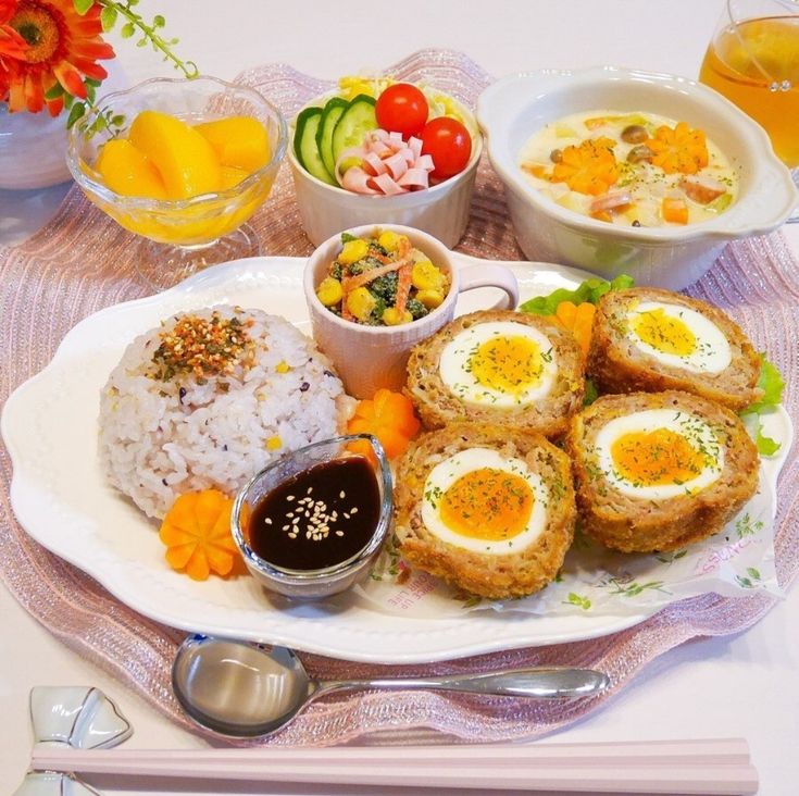 a white plate topped with food next to bowls of fruit and vegetables on a table