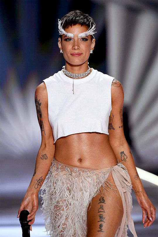 a woman with tattoos on her body walking down a runway