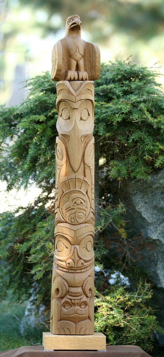 a carved wooden totem stands in front of some trees