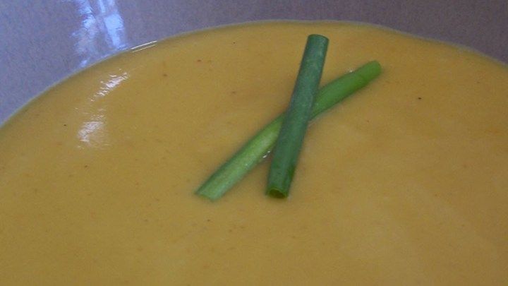 two green asparagus sticking out of a yellow soup