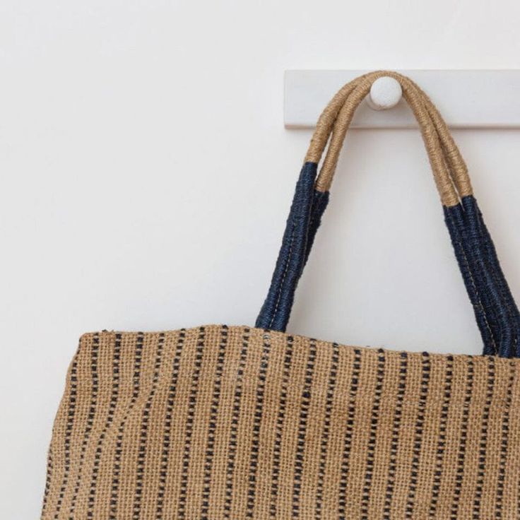 a brown and blue bag hanging from a hook on a white wall next to a door