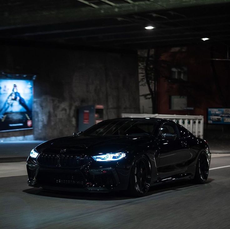 a black sports car driving down the road at night