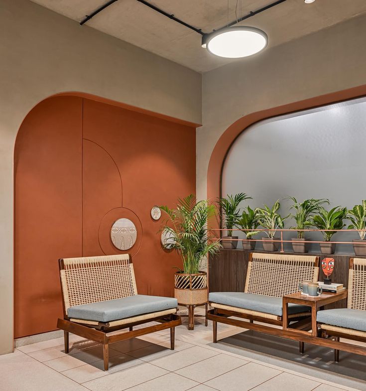 two chairs and a table in front of a window with potted plants on it