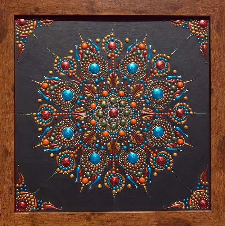 an artistic painting with beads and stones in a wooden frame on a black background,