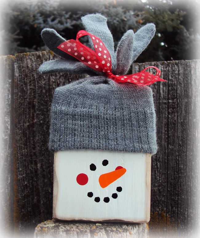 a wooden block with a snowman painted on it and a red ribbon tied around the top