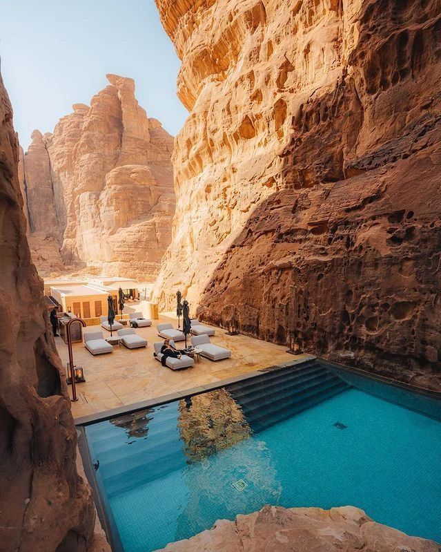 an outdoor swimming pool in the middle of some mountains