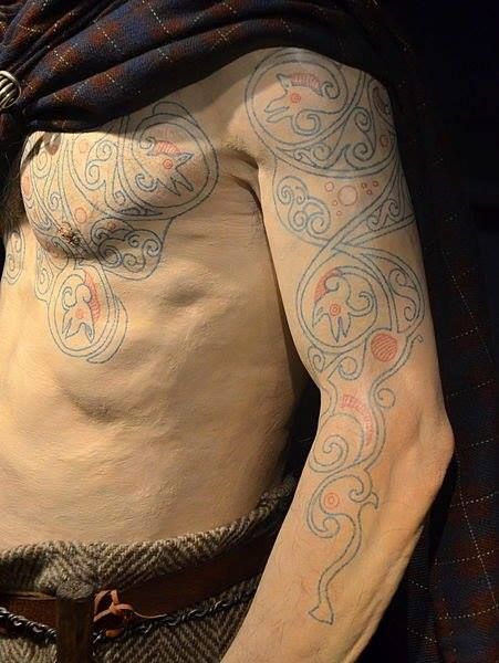 a man with tattoos on his chest and arms