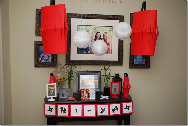 a table topped with red lanterns and pictures next to a framed photo on the wall