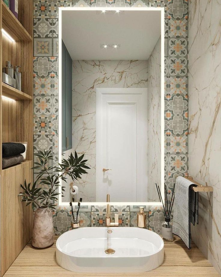 a white sink sitting under a bathroom mirror next to a wooden shelf with potted plants