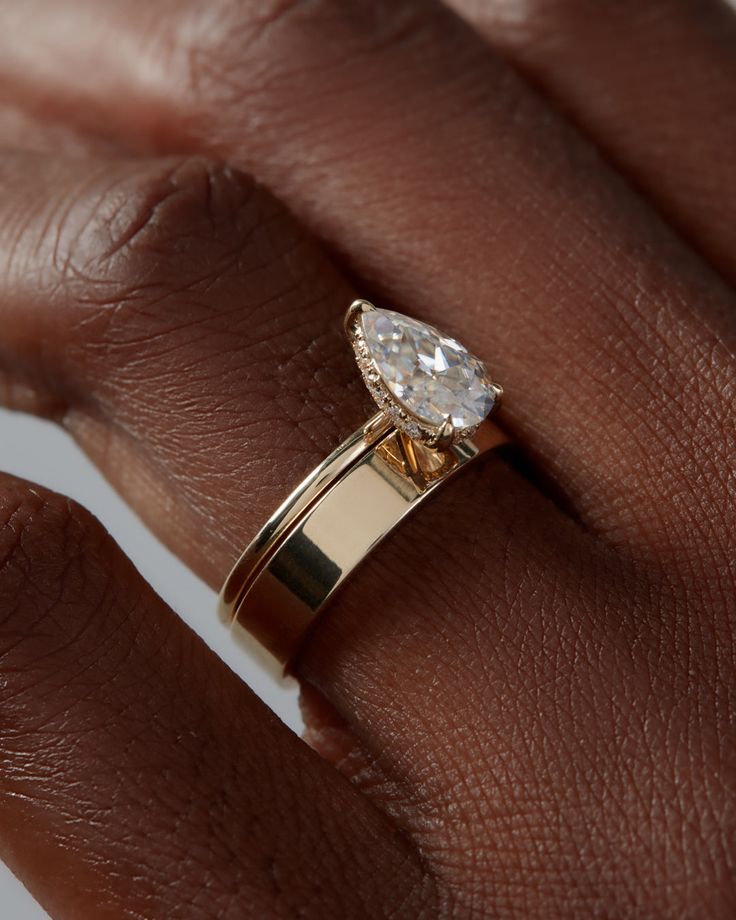 a woman's hand with a gold ring and a white diamond on the band