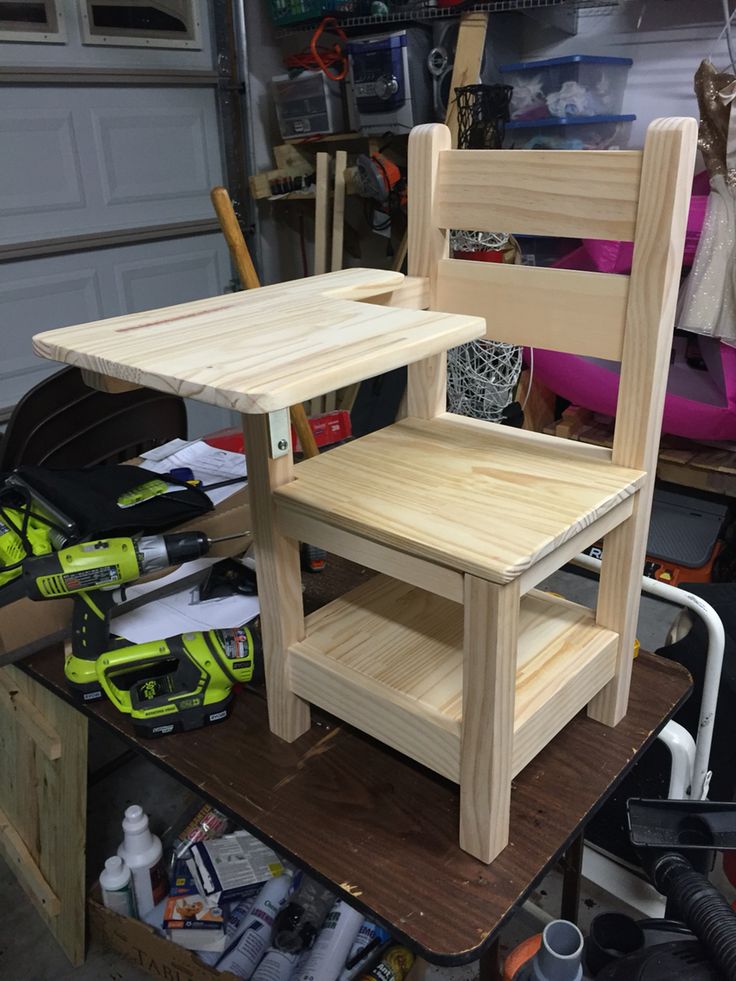 a chair made out of wood sitting on top of a wooden table in a garage