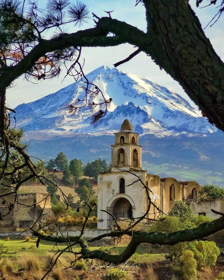 an old church in the foreground with a snow - capped mountain in the background