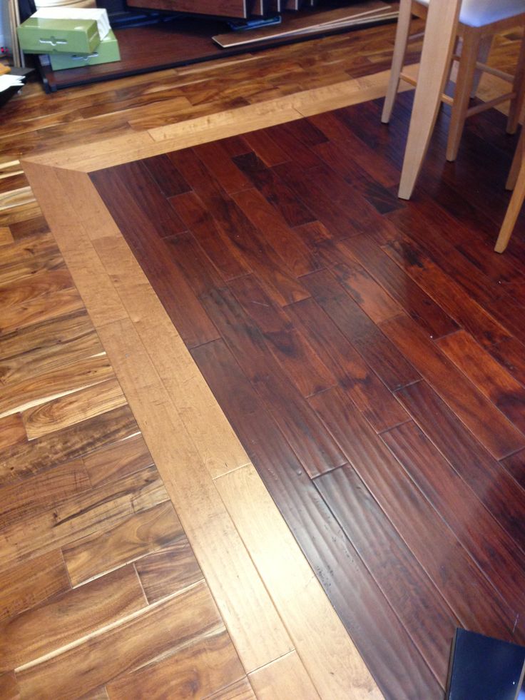 a wooden floor in a living room next to a dining room table and bookshelf