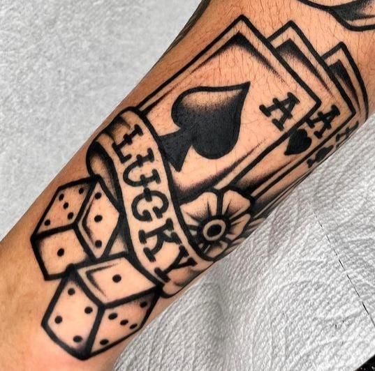 a black and white tattoo on the arm of a man with playing cards in it