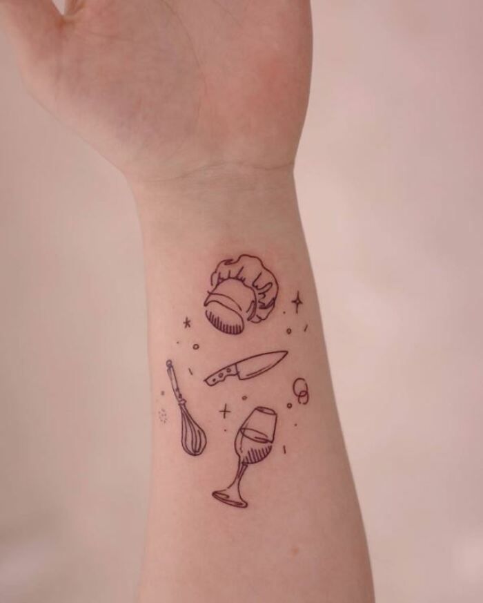 a person with a tattoo on their arm holding a knife and some other things in the background